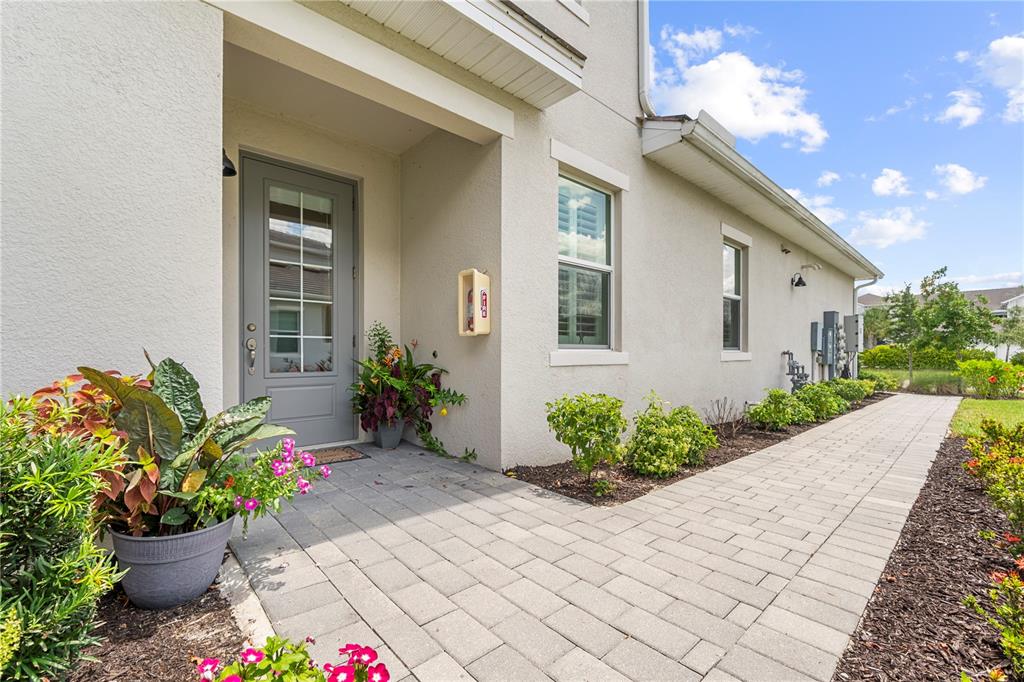 A paved walkway leads to the gray front door of a light-colored stucco home — 15983 GRASSLAND LANE UNIT 3411, PUNTA GORDA, FL