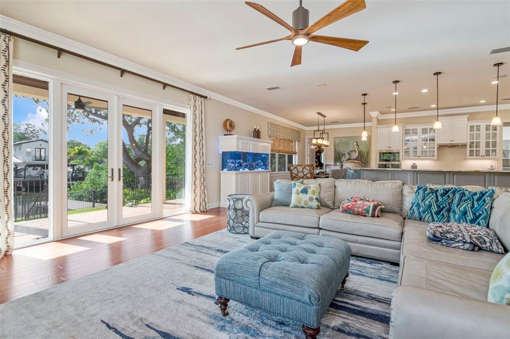 A living room with a sectional sofa, blue ottoman, aquarium, and glass doors to a deck — 2212 S OCCIDENT STREET, TAMPA, FL