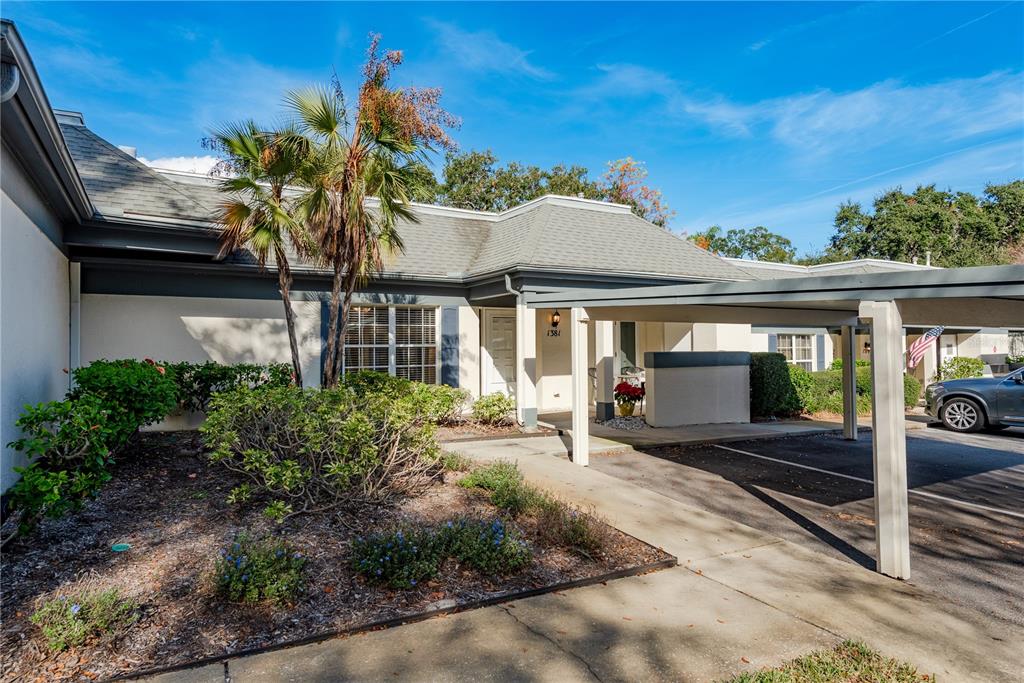 A single-story house with a covered carport, a palm tree, and a landscaped front yard — 1381 N MCMULLEN BOOTH ROAD UNIT 1381, CLEARWATER, FL