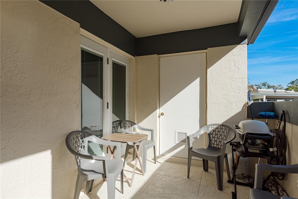 A covered balcony features a small table, four chairs, and a portable grill — 1381 N MCMULLEN BOOTH ROAD UNIT 1381, CLEARWATER, FL