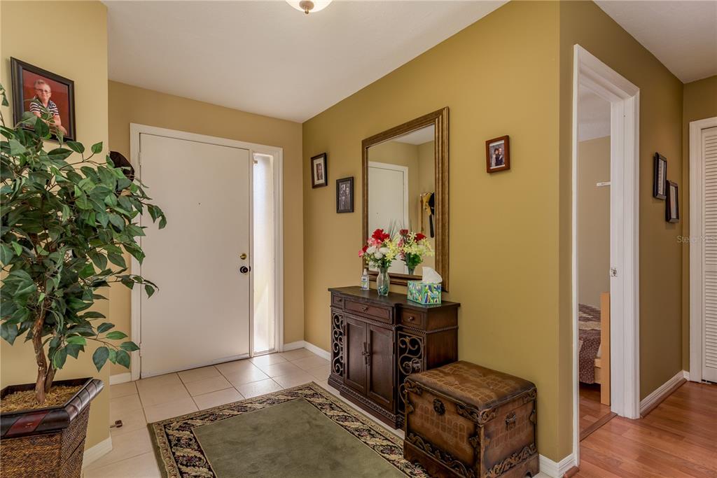 An entryway features a tiled floor, a wooden console table with a mirror, and a plant — 1381 N MCMULLEN BOOTH ROAD UNIT 1381, CLEARWATER, FL
