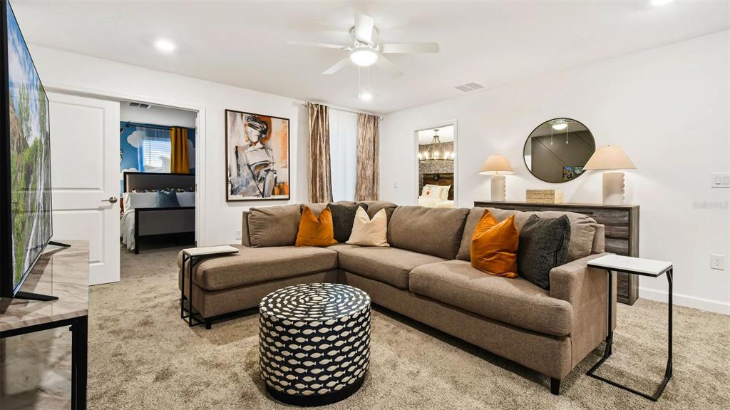 A living room features a brown sectional sofa, a patterned ottoman, and two side tables — 2993 PROTAGONIST STREET, KISSIMMEE, FL