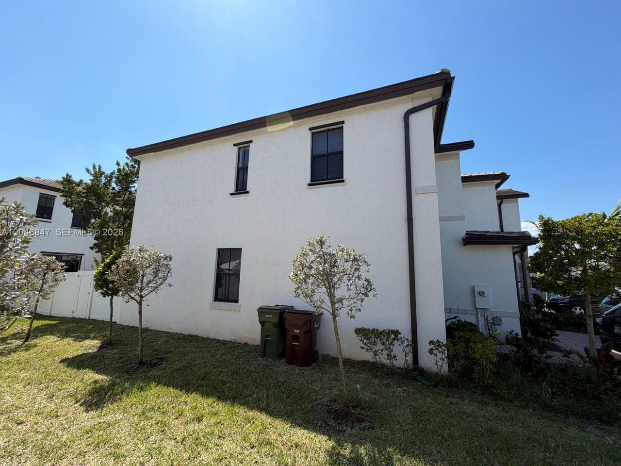 The exterior of a two-story white stucco house features dark window frames and downspouts — 3338 W 112th St, Hialeah FL 33018, HIALEAH, FL