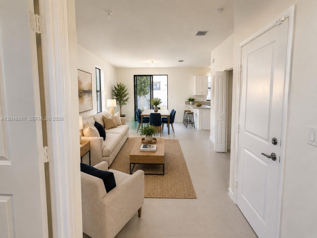 An open-concept living and dining area features light tile floors and a modern kitchen — 3338 W 112th St, Hialeah FL 33018, HIALEAH, FL