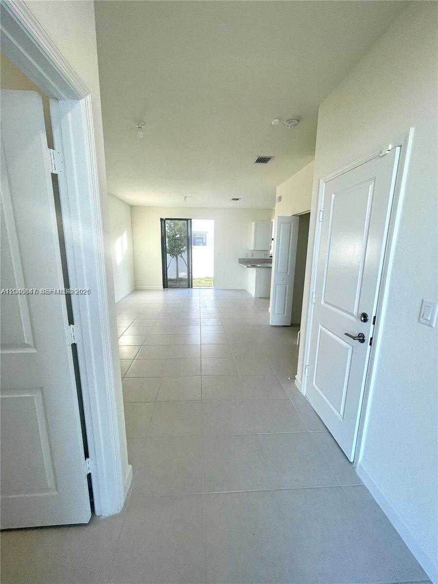 A view from a hallway looking into an open-concept living area with tile flooring — 3338 W 112th St, Hialeah FL 33018, HIALEAH, FL
