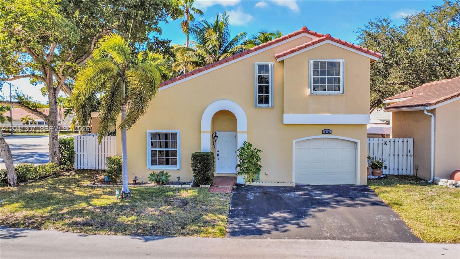 A two-story house with a tan stucco exterior, a front-facing garage, and a palm tree — 12797 NW 13th St, Sunrise FL 33323, SUNRISE, FL