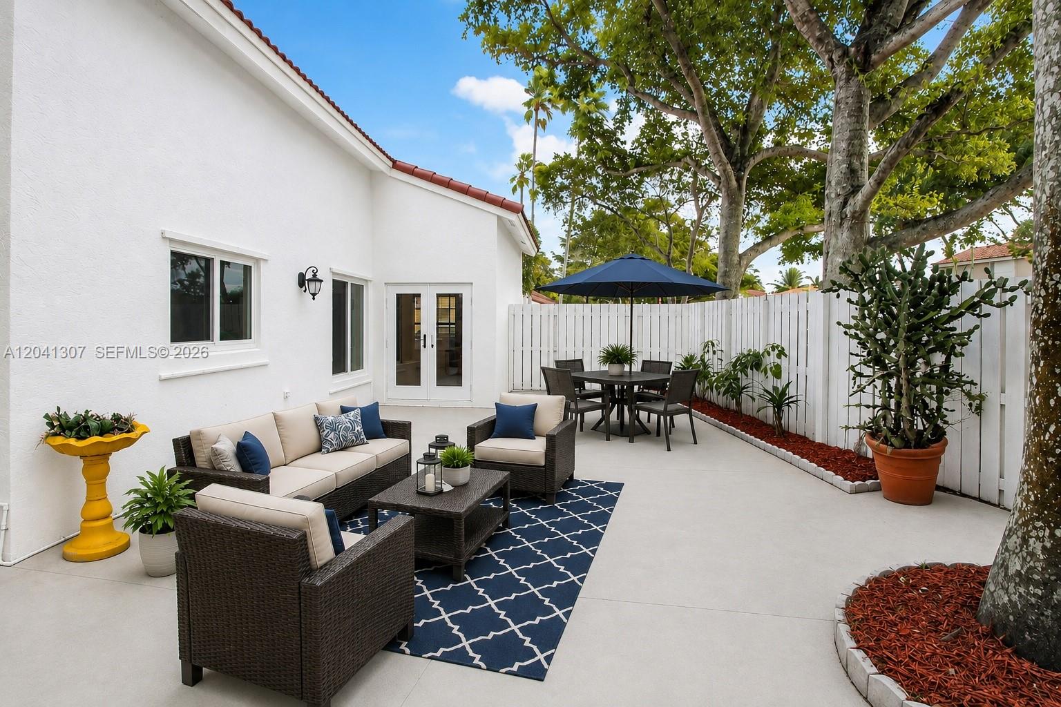 A patio features outdoor furniture, a blue umbrella, a patterned rug, and a large cactus — 12797 NW 13th St, Sunrise FL 33323, SUNRISE, FL