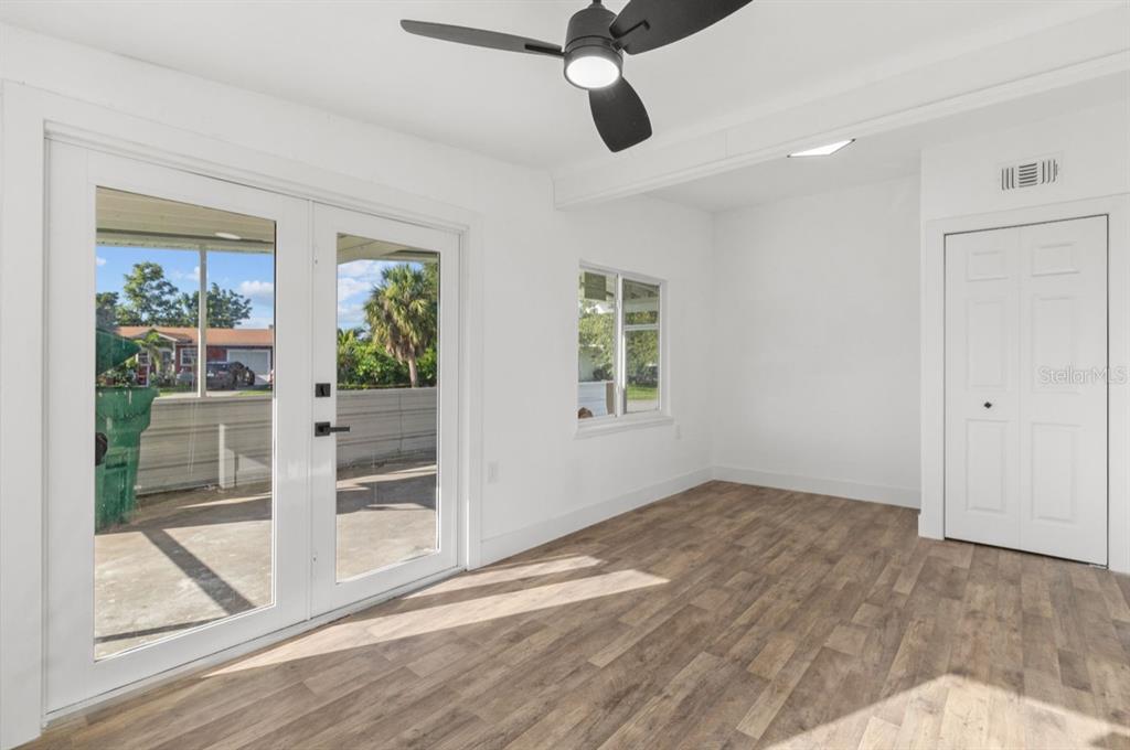 A bright room features wood-look flooring, a ceiling fan, French doors, and a white closet — 2360 EDNOR STREET, PORT CHARLOTTE, FL