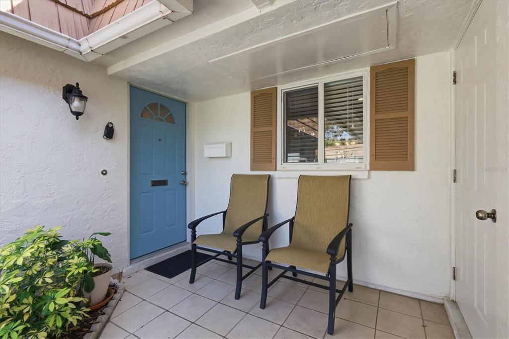 A covered front porch features a blue door, two chairs, and a window with shutters — 2713 RIVERBLUFF COURT UNIT V101, SARASOTA, FL