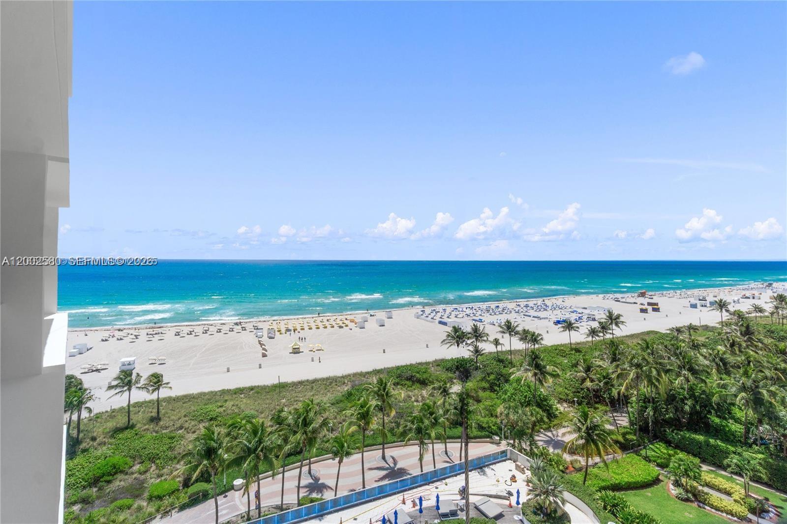 An elevated view of a sandy beach, ocean, and palm trees from a balcony — 100 Lincoln Rd # 1046, Miami Beach FL 33139, MIAMI BEACH, FL