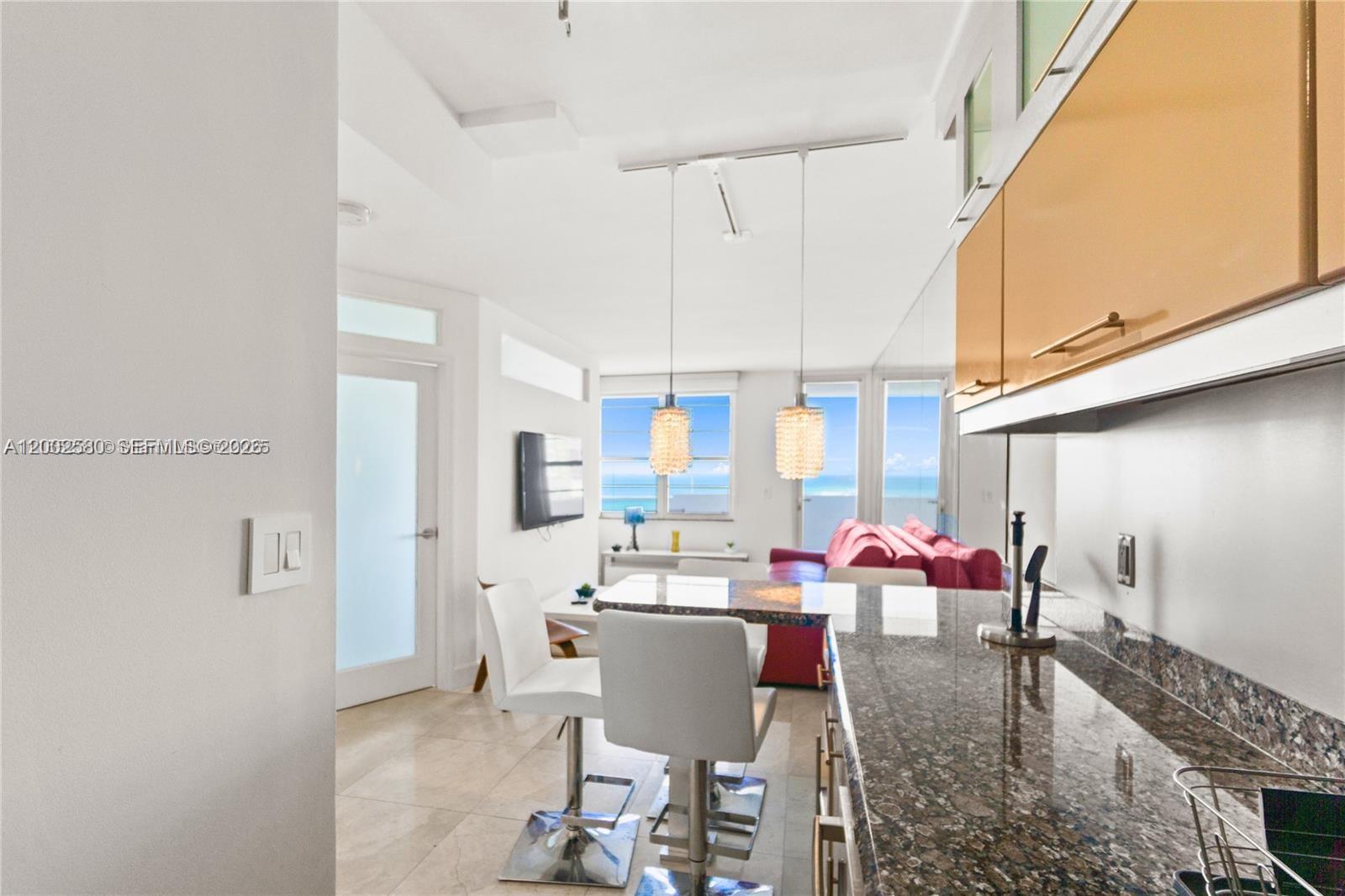 A kitchen with granite countertops overlooks a living area with ocean views and a sofa — 100 Lincoln Rd # 1046, Miami Beach FL 33139, MIAMI BEACH, FL