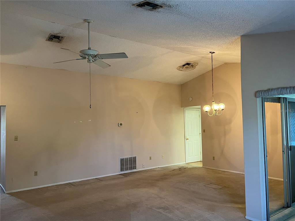 The rear exterior of a house features a screened-in patio and a grassy backyard — 10738 LAZY LAKE DR, ORLANDO, FL