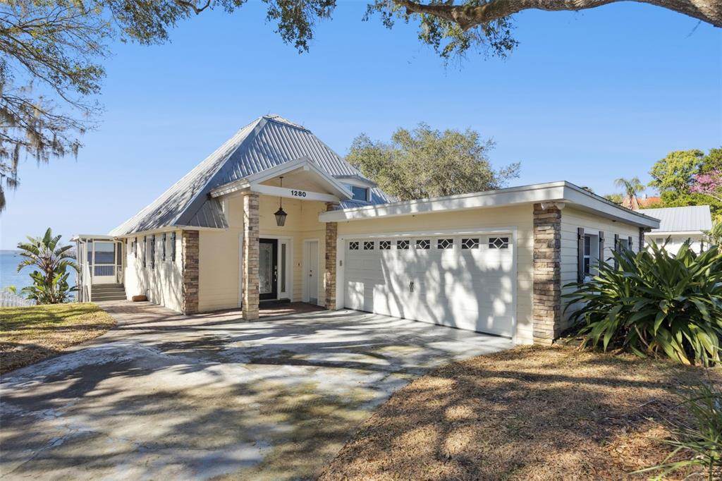 A single-story house with a metal roof, stone accents, and an attached two-car garage — 1280 N CROOKED LAKE DRIVE, BABSON PARK, FL