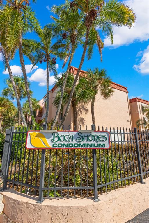 A sign for Boca Shores Condominium stands in front of a multi-story tan building — 8911 BLIND PASS ROAD UNIT 214, ST PETE BEACH, FL