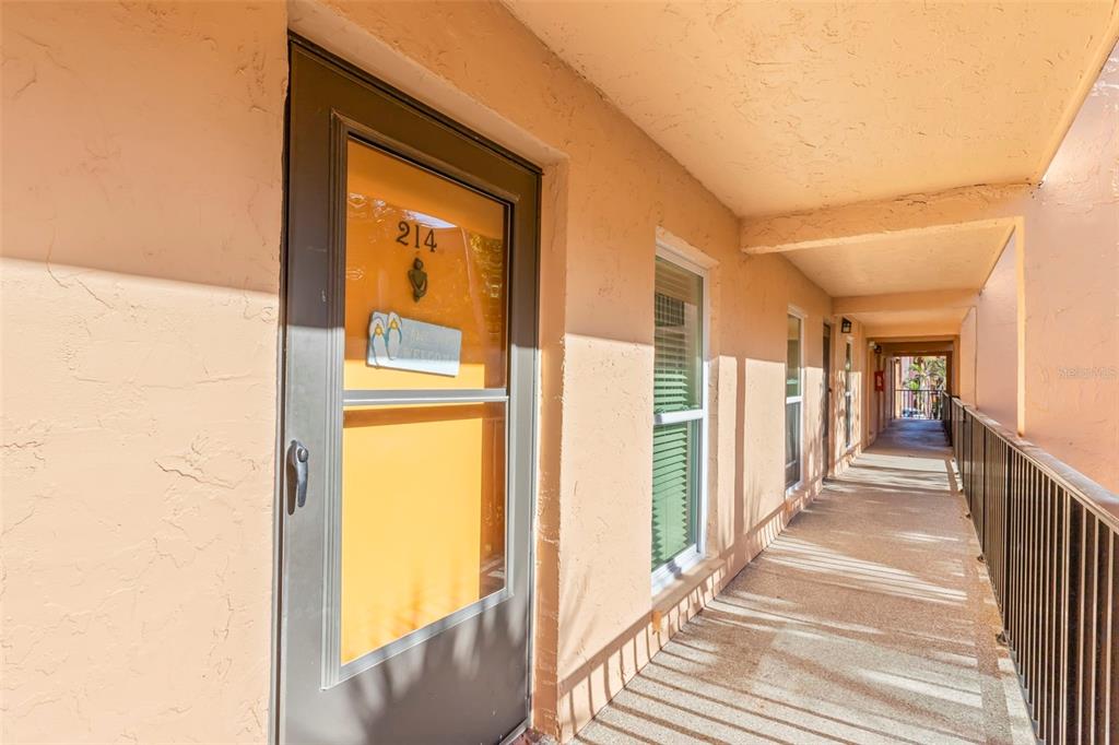 An exterior walkway leads to the front door of a unit marked with number 214 — 8911 BLIND PASS ROAD UNIT 214, ST PETE BEACH, FL
