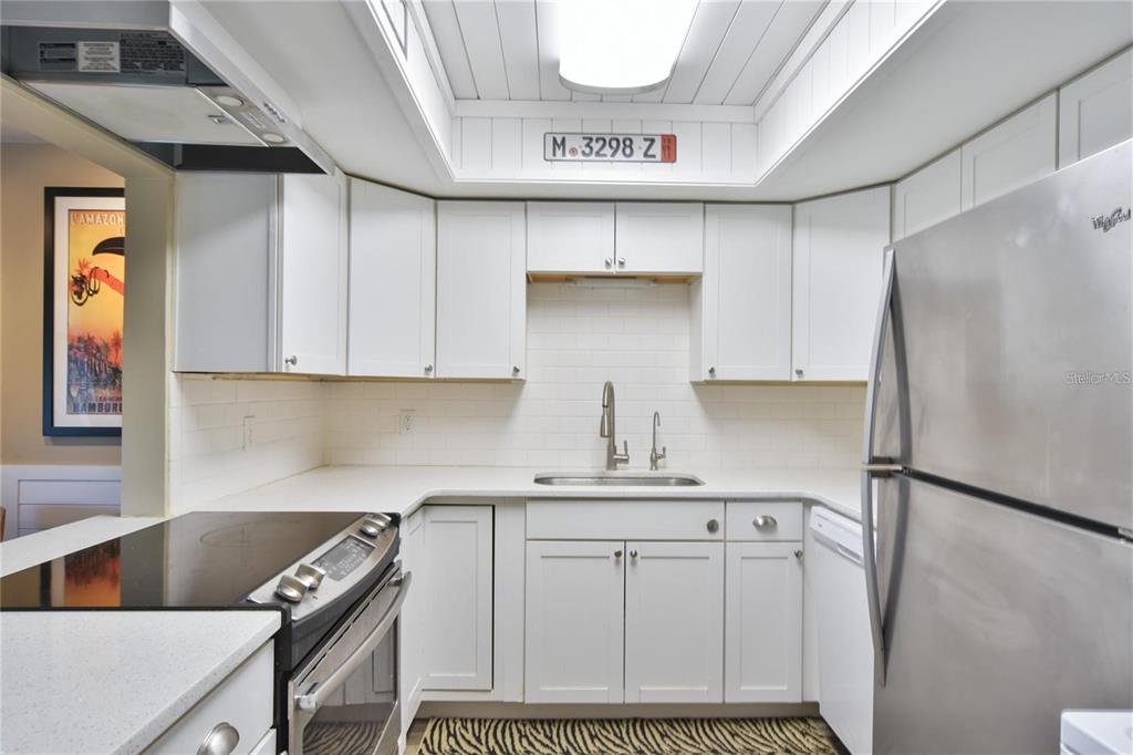 A kitchen with white cabinets, stainless steel appliances, a subway tile backsplash, and a skylight — 637 MIDWAY DRIVE UNIT B, OCALA, FL
