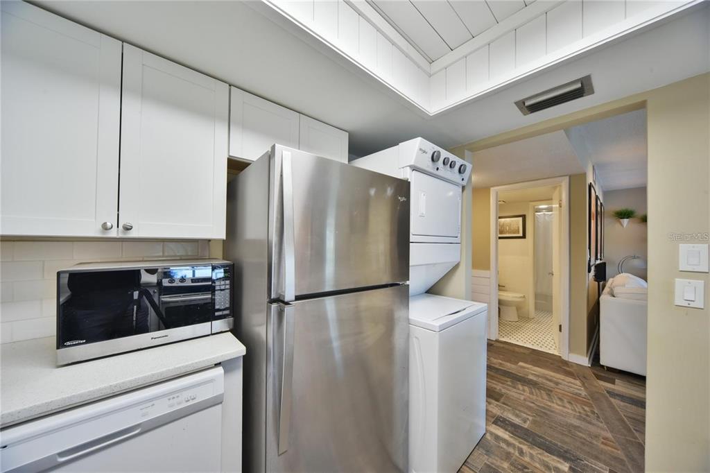 A kitchen featuring white cabinets, stainless steel appliances, and a stacked laundry unit — 637 MIDWAY DRIVE UNIT B, OCALA, FL