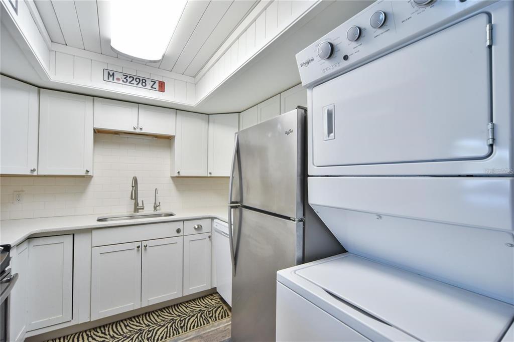 A kitchen with white cabinets, stainless steel refrigerator, and a stacked washer and dryer unit — 637 MIDWAY DRIVE UNIT B, OCALA, FL