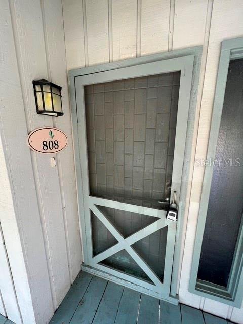 A light blue screen door with an X-pattern base is mounted at a building entrance — 808 PINEWOOD COURT UNIT 3138/9, HAINES CITY, FL