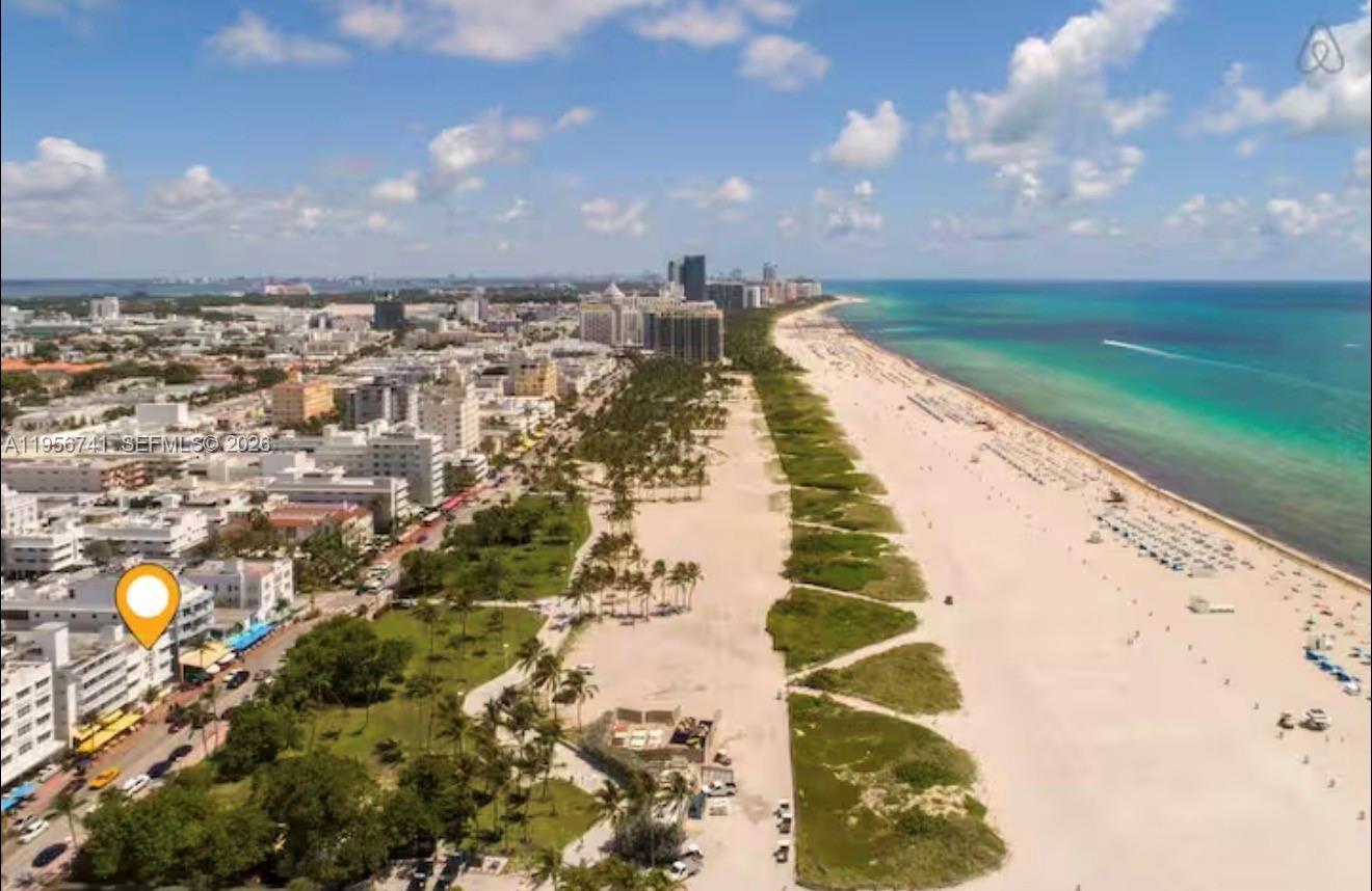 An aerial view shows a sandy beach, palm trees, and a coastal city skyline — 1036 Ocean Dr # B201, Miami Beach FL 33139, MIAMI BEACH, FL