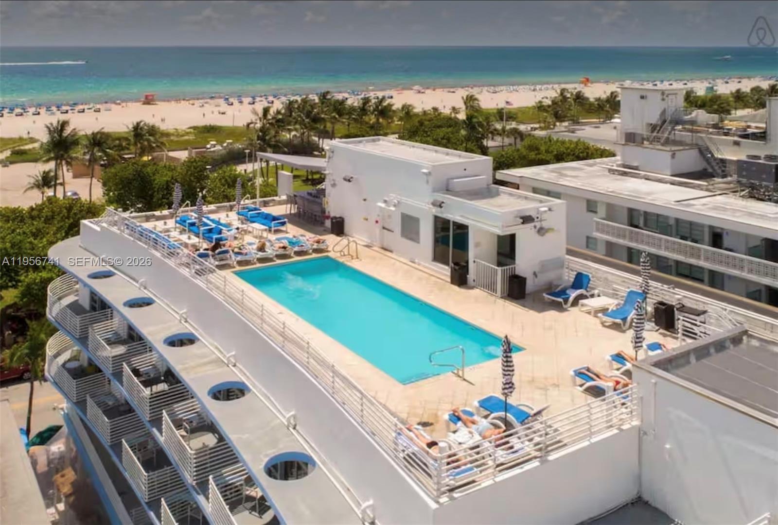 An aerial view of a rooftop swimming pool with lounge chairs overlooking a sandy beach — 1036 Ocean Dr # B201, Miami Beach FL 33139, MIAMI BEACH, FL