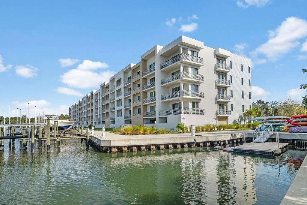 A multi-story white apartment building stands beside a boat dock on a sunny day — 1709 N TAMIAMI TRAIL UNIT 201, SARASOTA, FL