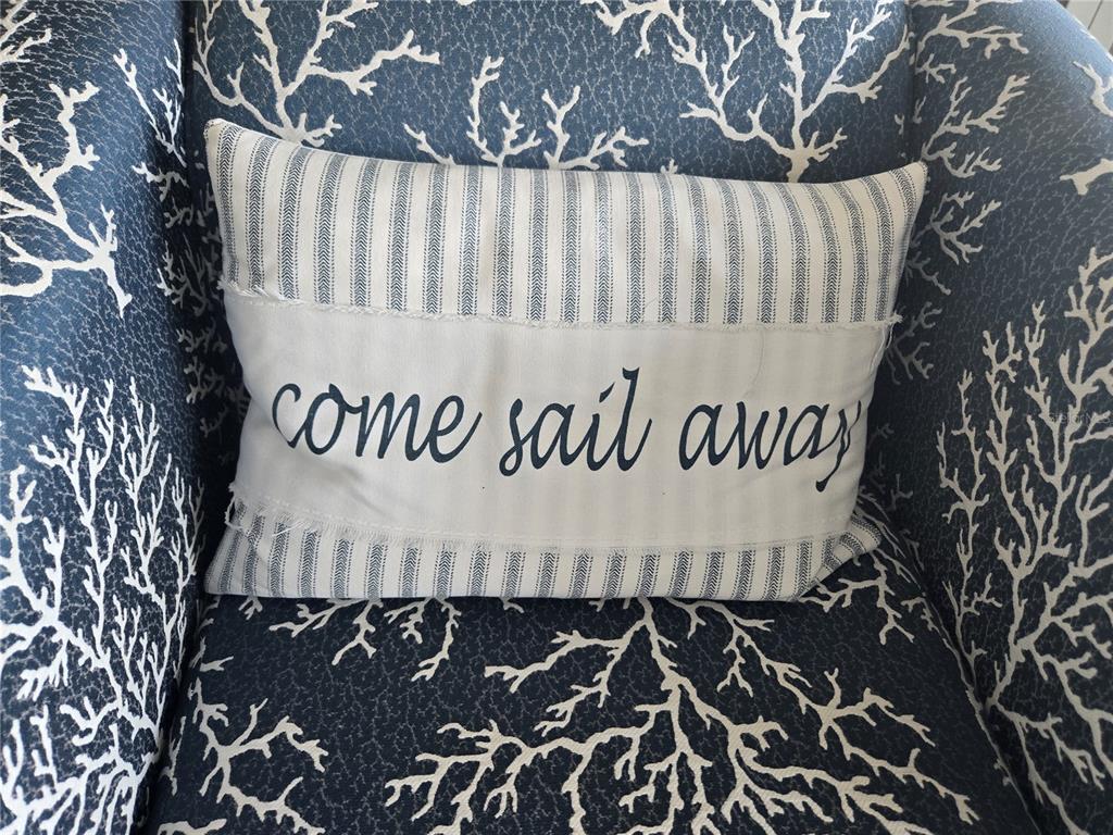 A decorative throw pillow with the text come sail away sits on a coral-patterned chair — 1709 N TAMIAMI TRAIL UNIT 201, SARASOTA, FL