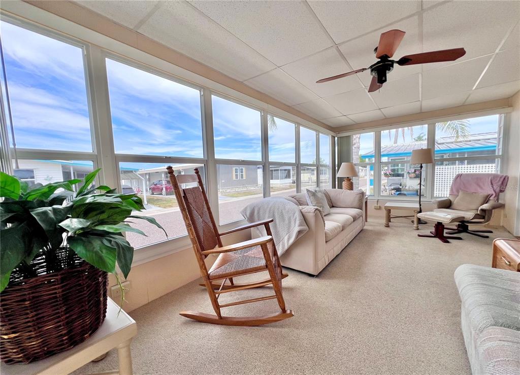 A sunroom features a rocking chair, a sofa, a recliner, and large windows — 1100 BELCHER ROAD S UNIT 663, LARGO, FL