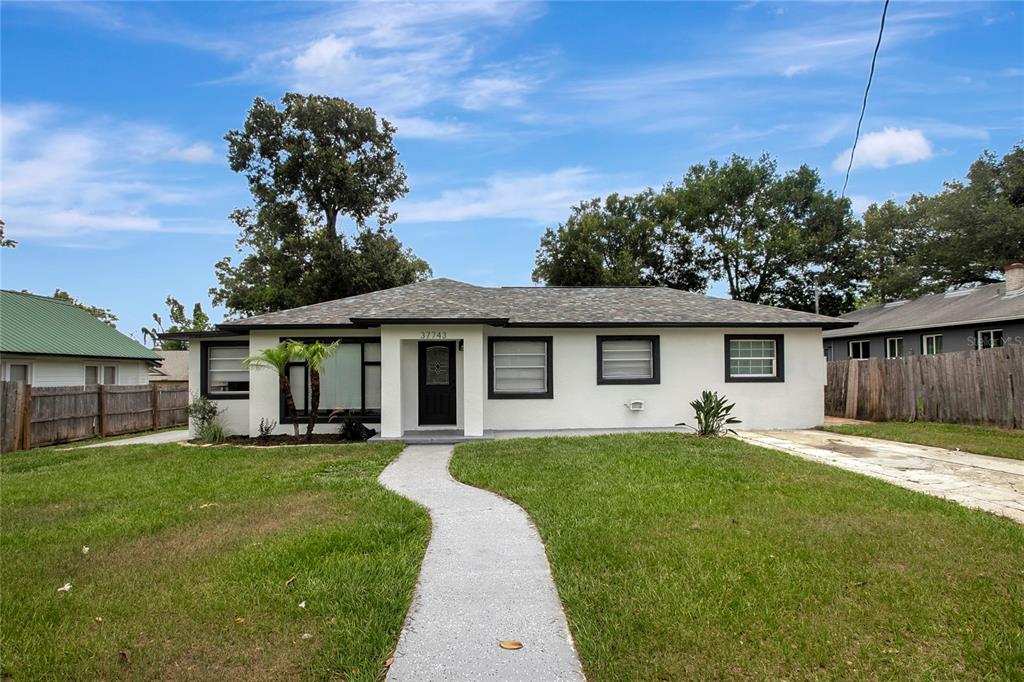 A single-story white house with a dark roof, black window frames, and a front walkway — 37743 FLORIDA AVENUE, DADE CITY, FL