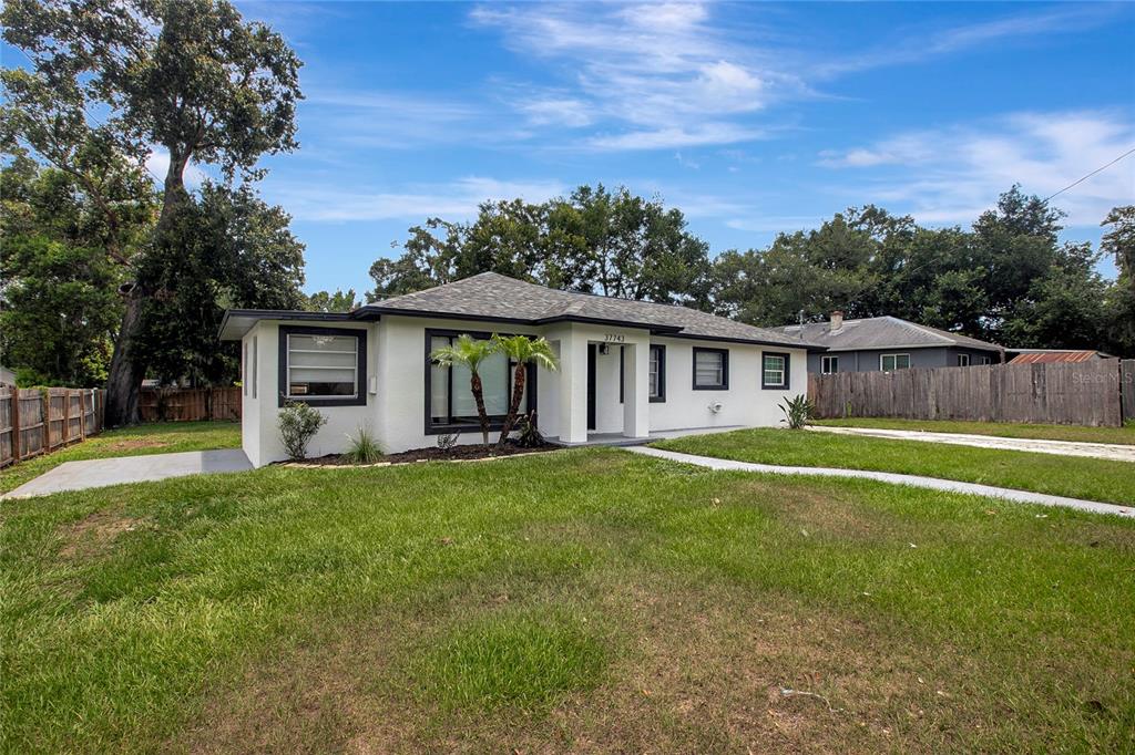 A white, single-story house with a dark-trimmed exterior sits on a grassy lot — 37743 FLORIDA AVENUE, DADE CITY, FL