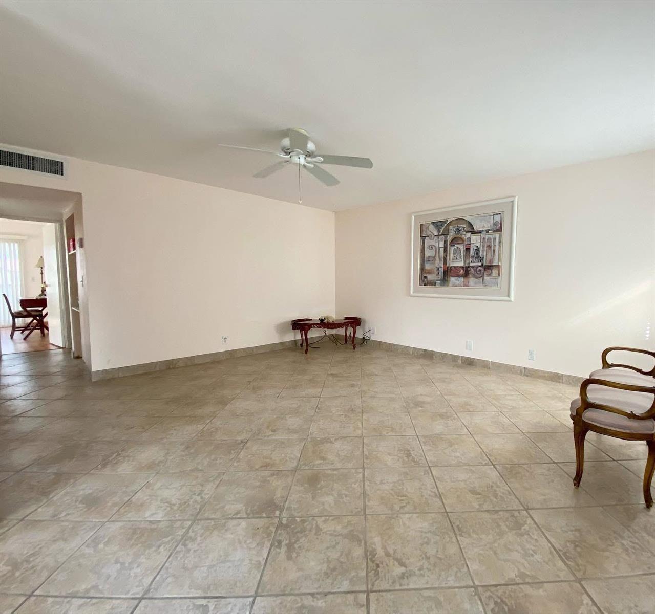 A spacious living room features light-colored walls, large beige floor tiles, and a ceiling fan — 568 Brittany L, Delray Beach FL 33446, DELRAY BEACH, FL