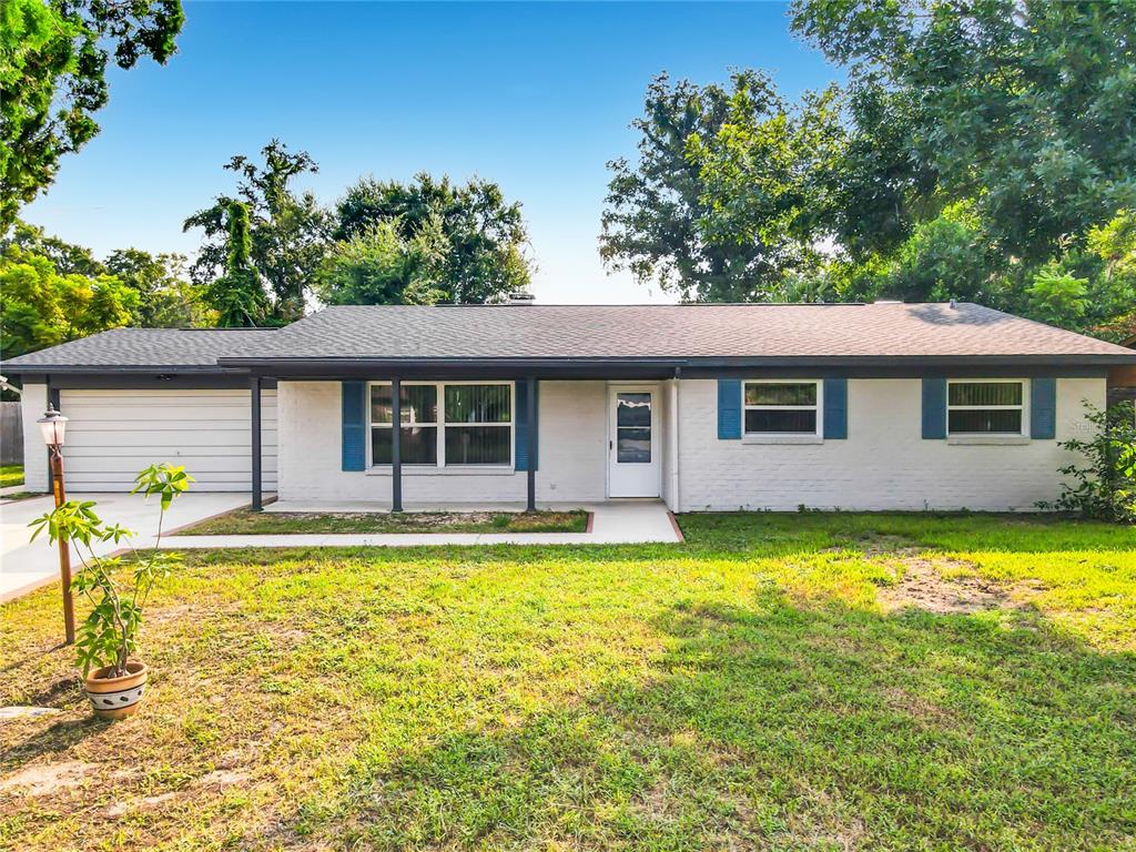 A single-story white brick house with a gray roof, blue shutters, and an attached garage — 605 WILLIAMSBURG DRIVE, DAYTONA BEACH, FL
