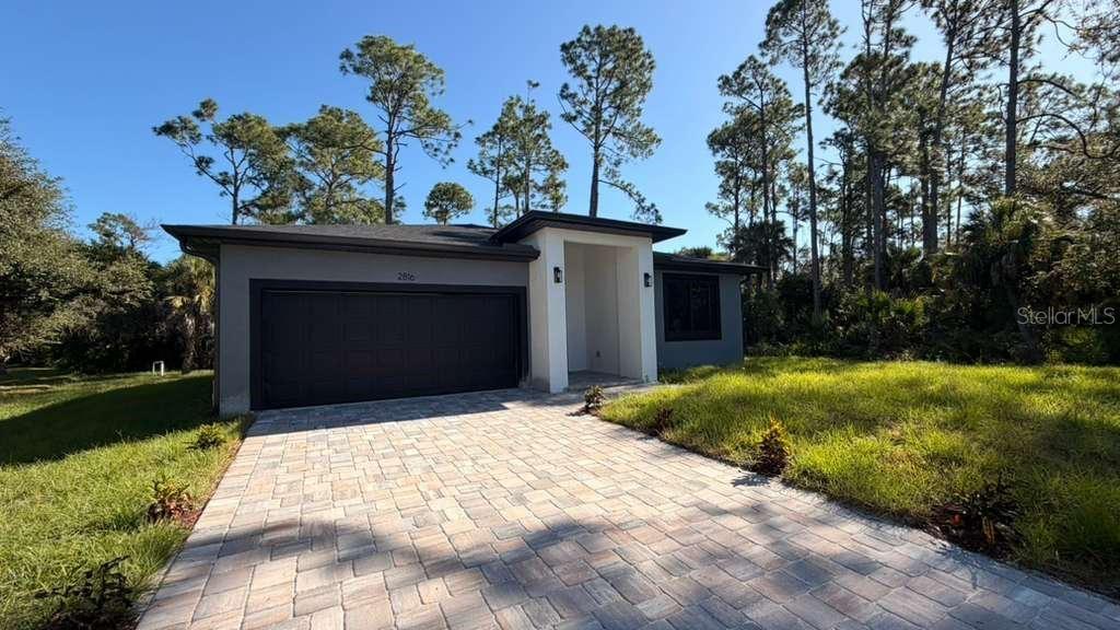 A modern single-story house features a dark garage door and a paved driveway — 2816 SILAS AVENUE, NORTH PORT, FL