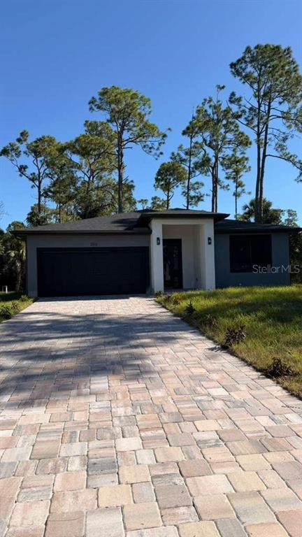 A single-story house with a dark garage door and a paved driveway under a blue sky — 2816 SILAS AVENUE, NORTH PORT, FL