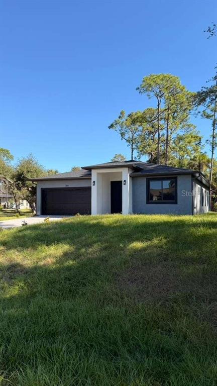 A modern, single-story house with a dark garage door and gray stucco exterior — 2816 SILAS AVENUE, NORTH PORT, FL