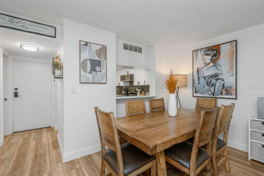 A dining area with a wooden table, six chairs, and a view into the kitchen — 2614 COVE CAY DRIVE UNIT 102, CLEARWATER, FL
