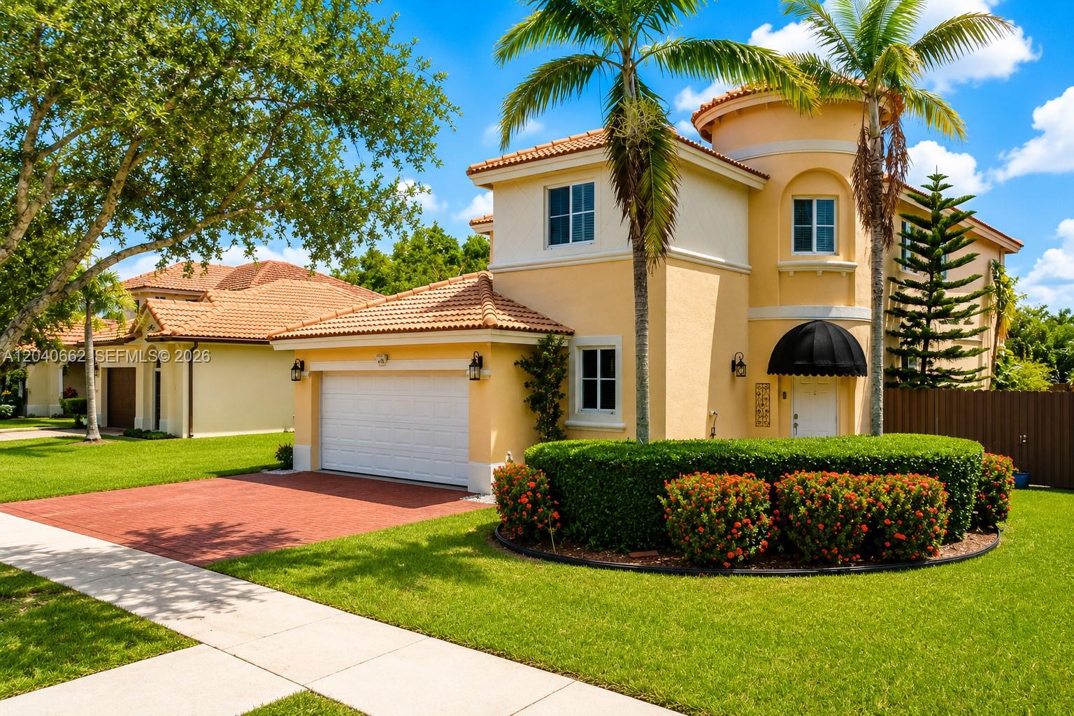 A two-story yellow stucco house with a tile roof, garage, and landscaped front yard — 116 SE 22nd Ter, Homestead FL 33033, HOMESTEAD, FL