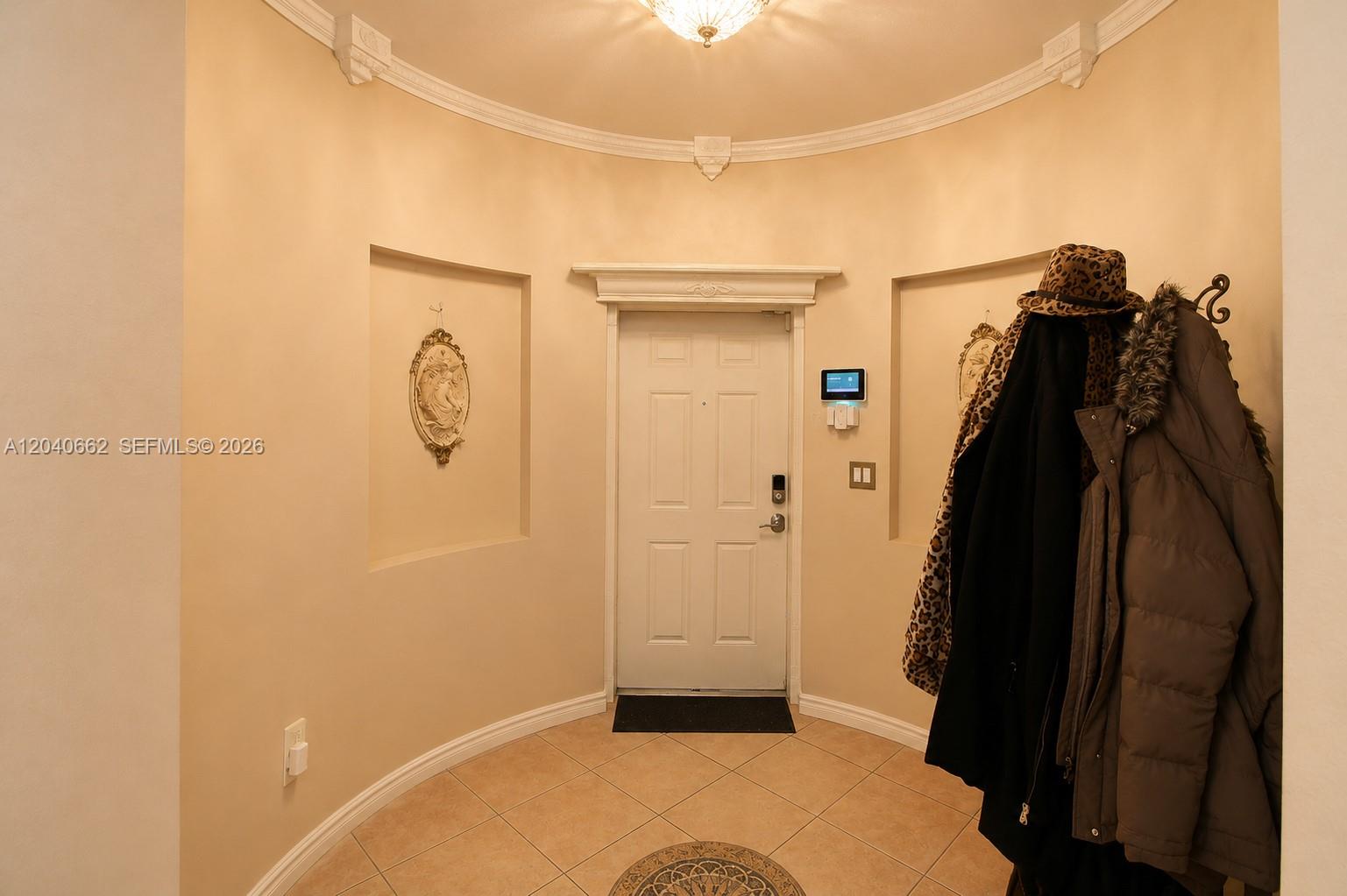 An entryway features a curved wall, a white door, tiled floors, and a coat rack — 116 SE 22nd Ter, Homestead FL 33033, HOMESTEAD, FL