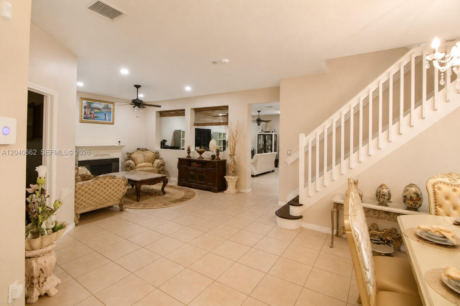 A living room with tile floors, a fireplace, and a staircase leads to a dining area — 116 SE 22nd Ter, Homestead FL 33033, HOMESTEAD, FL
