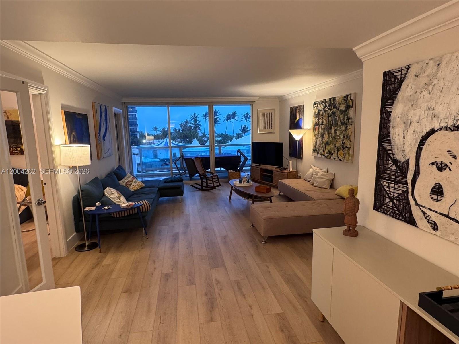 A living room features two sofas, a wooden rocking chair, and a view of palm trees — 5151 Collins Ave # 436, Miami Beach FL 33140, MIAMI BEACH, FL