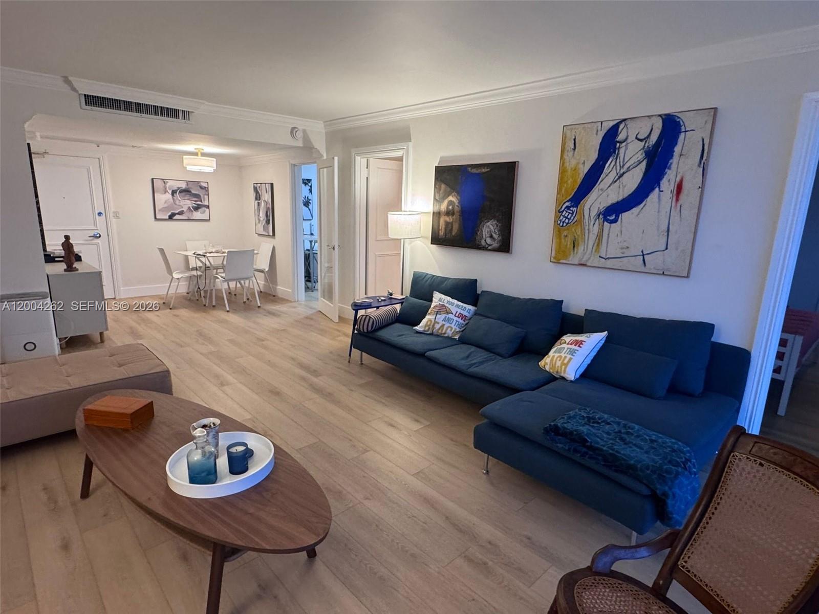 A living room features a blue sectional sofa, a wooden coffee table, and light flooring — 5151 Collins Ave # 436, Miami Beach FL 33140, MIAMI BEACH, FL