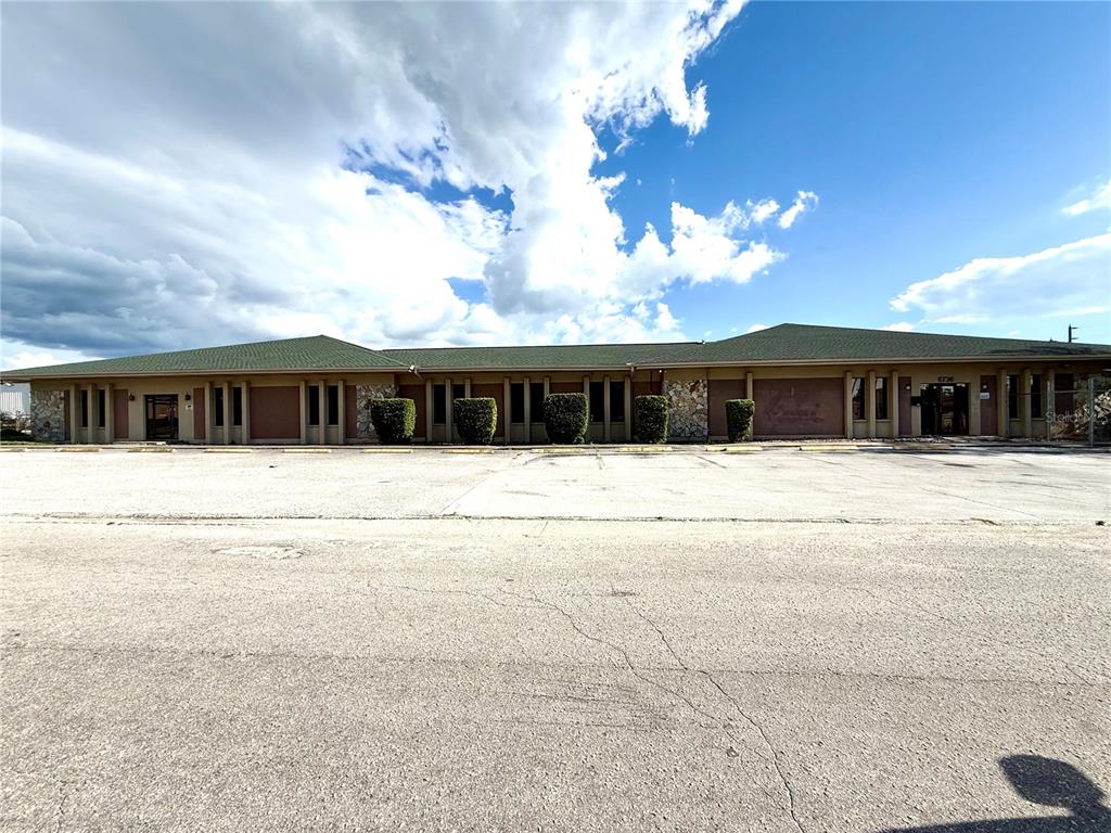 A low-rise commercial building with a green roof, stone accents, and a large parking lot — 6736 COMMERCE AVENUE, PORT RICHEY, FL