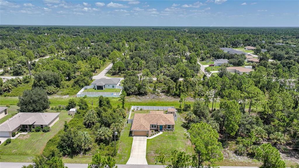 An aerial view shows a single-story house with a tan roof and a concrete driveway — 5742 JANUS AVENUE, NORTH PORT, FL