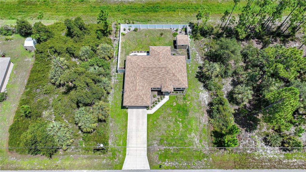 An aerial view shows a single-story house with a shingled roof and a fenced backyard — 5742 JANUS AVENUE, NORTH PORT, FL