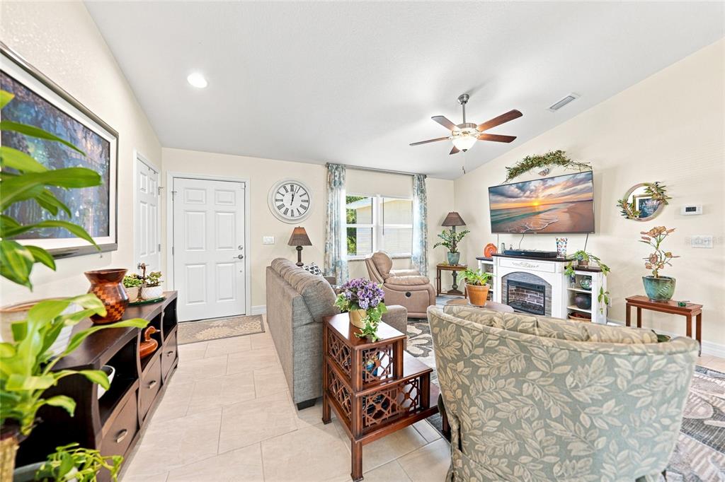 A living room features a fireplace, a television, a ceiling fan, and tiled flooring — 5742 JANUS AVENUE, NORTH PORT, FL