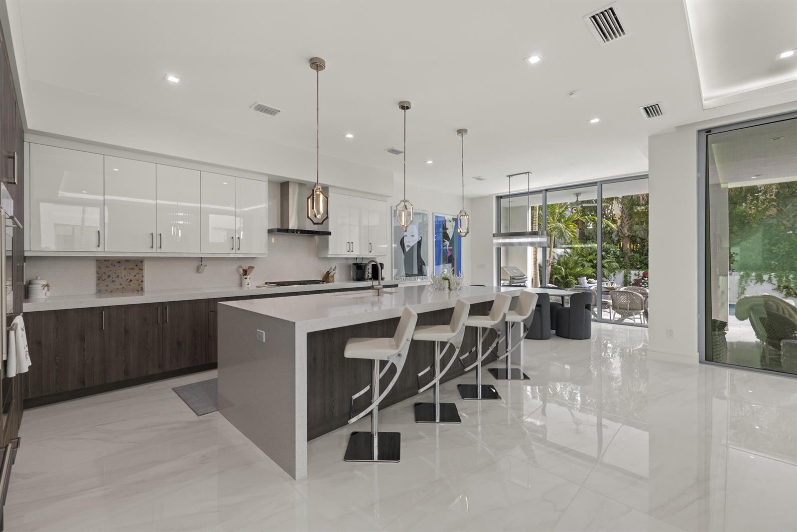A modern kitchen features white upper cabinets, dark wood lower cabinets, and a large quartz island — 402 Ocean One Lane, Juno Beach FL 33408, JUNO BEACH, FL