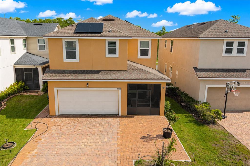 An exterior view of a two-story orange house with a paved driveway and garage — 8032 SCAGEL STREET, ORLANDO, FL