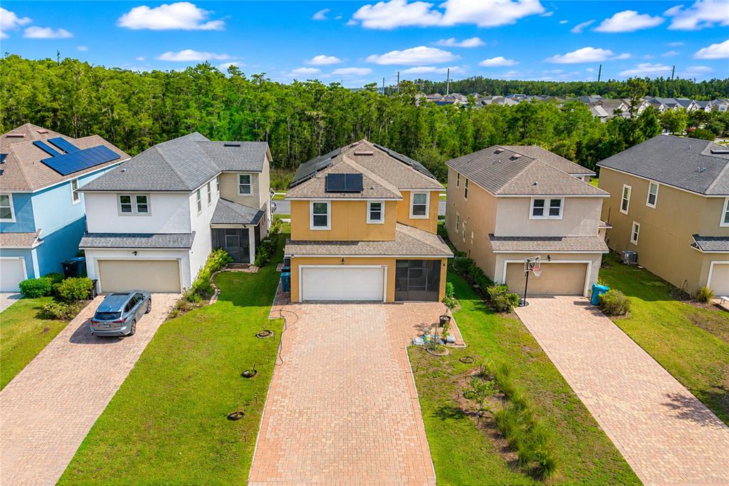 An aerial view shows three suburban houses with paved driveways and green lawns — 8032 SCAGEL STREET, ORLANDO, FL