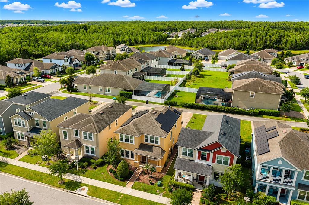 An aerial view shows a suburban neighborhood with detached houses, green lawns, and swimming pools — 8032 SCAGEL STREET, ORLANDO, FL