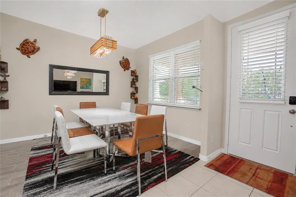 A dining room features a marble-topped table, modern chairs, a chandelier, and a patterned rug — 8032 SCAGEL STREET, ORLANDO, FL